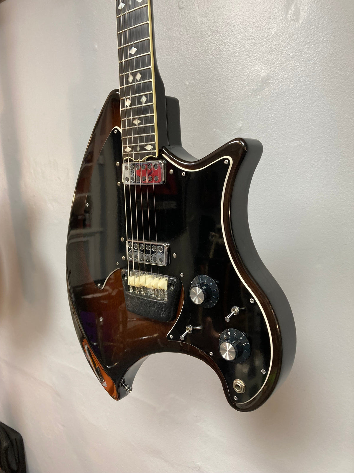 Ovation Deacon 1973-1975 sunburst electric guitar, well-preserved with minor wear, displayed on a wall, showcasing strings, dials, and neck details.