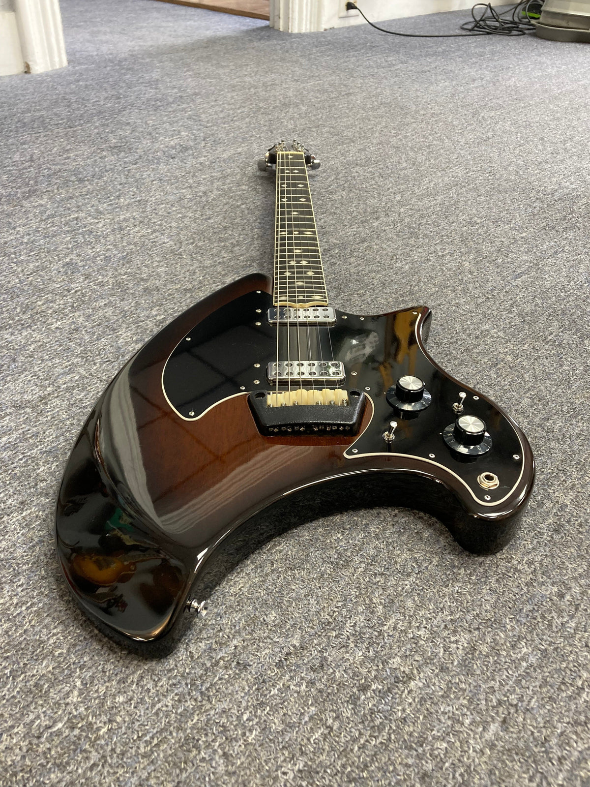 Ovation Deacon 1973-1975 Sunburst Electric Guitar lying on a grey carpet, highlighting its vintage charm and well-preserved condition, with close-up details of dials and bridge.