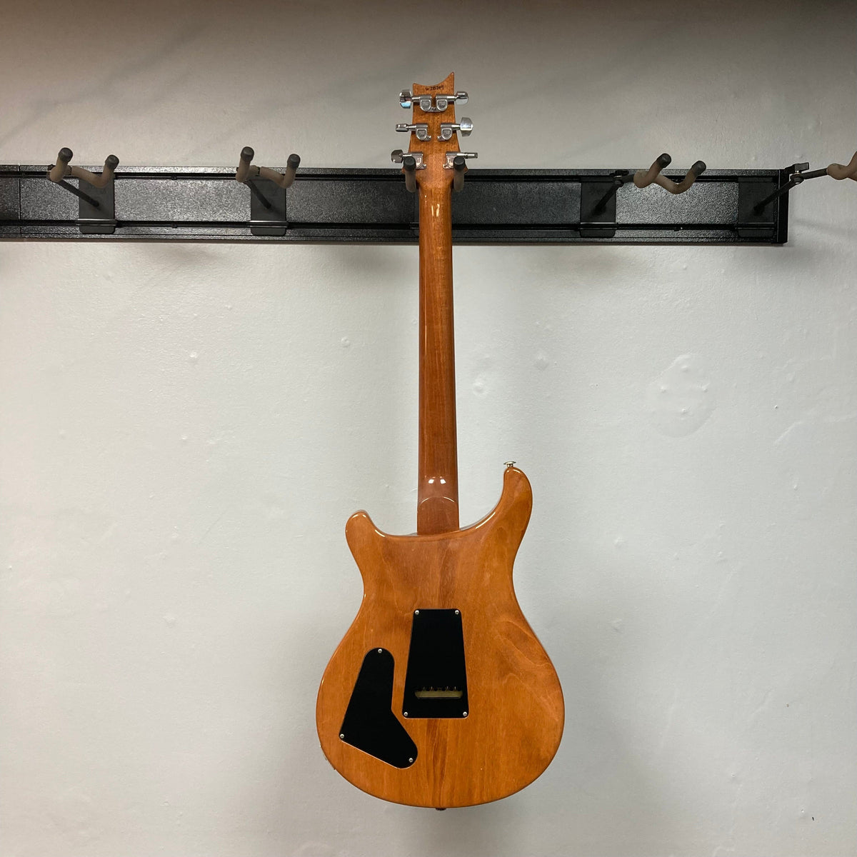 PRS 1996 Gold Top guitar mounted on a wall, showcasing its lustrous finish and craftsmanship. Includes original hard case for protection.