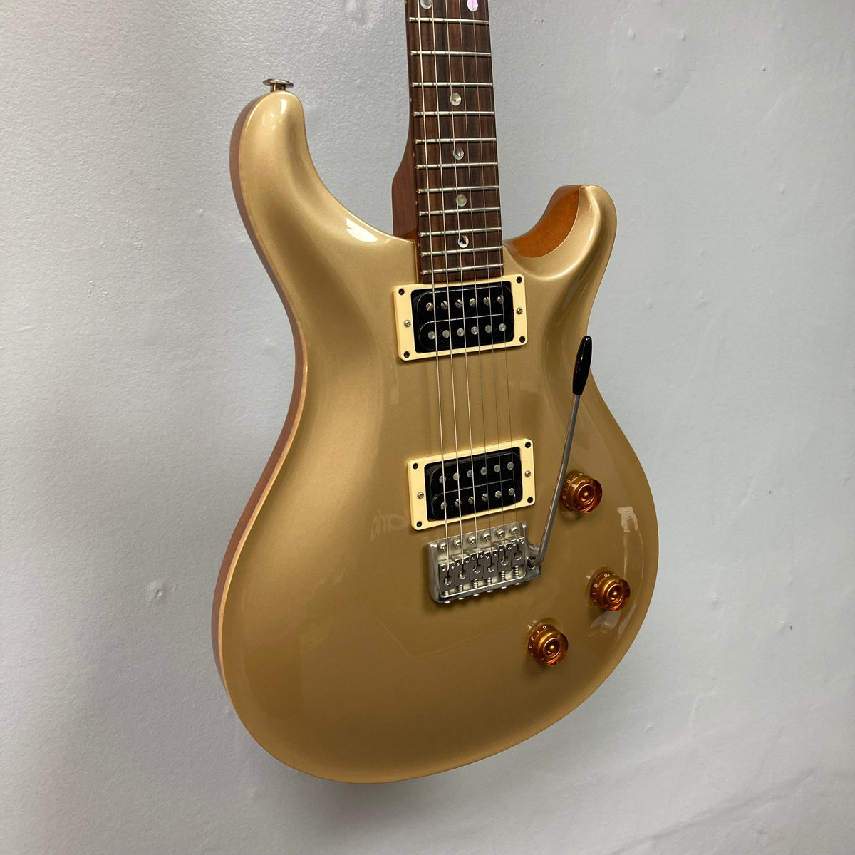 PRS 1996 Gold Top electric guitar mounted on a wall, showcasing its lustrous finish and impeccable craftsmanship.
