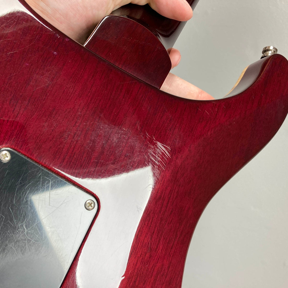 Close-up of the back of a red PRS Custom 24 Angry Larry 2011 electric guitar by PRS, showing noticeable scratches and wear near the neck joint and control plate—details that highlight its well-loved character and the distinctive tone delivered by its humbuckers. Includes case.