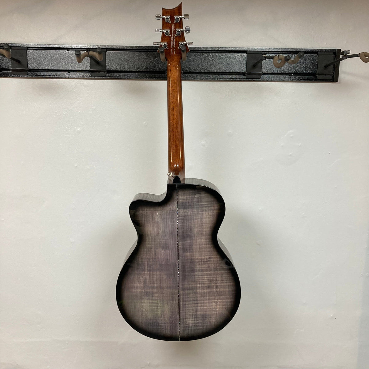 PRS SE A50E Charcoal Burst w/Case Used; displayed hanging, showcasing its solid spruce top and maple back, ideal for both picking and fingerstyle techniques.