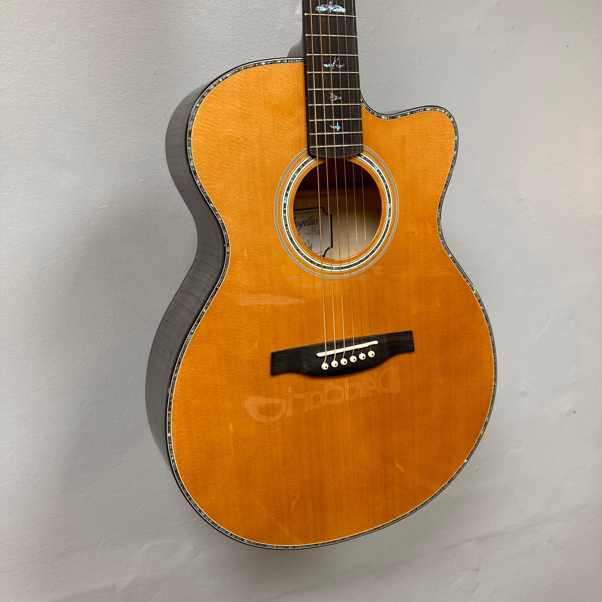 PRS SE A50E Charcoal Burst guitar with maple back, spruce top, and Fishman GT1 pickup system, displayed on a wall.