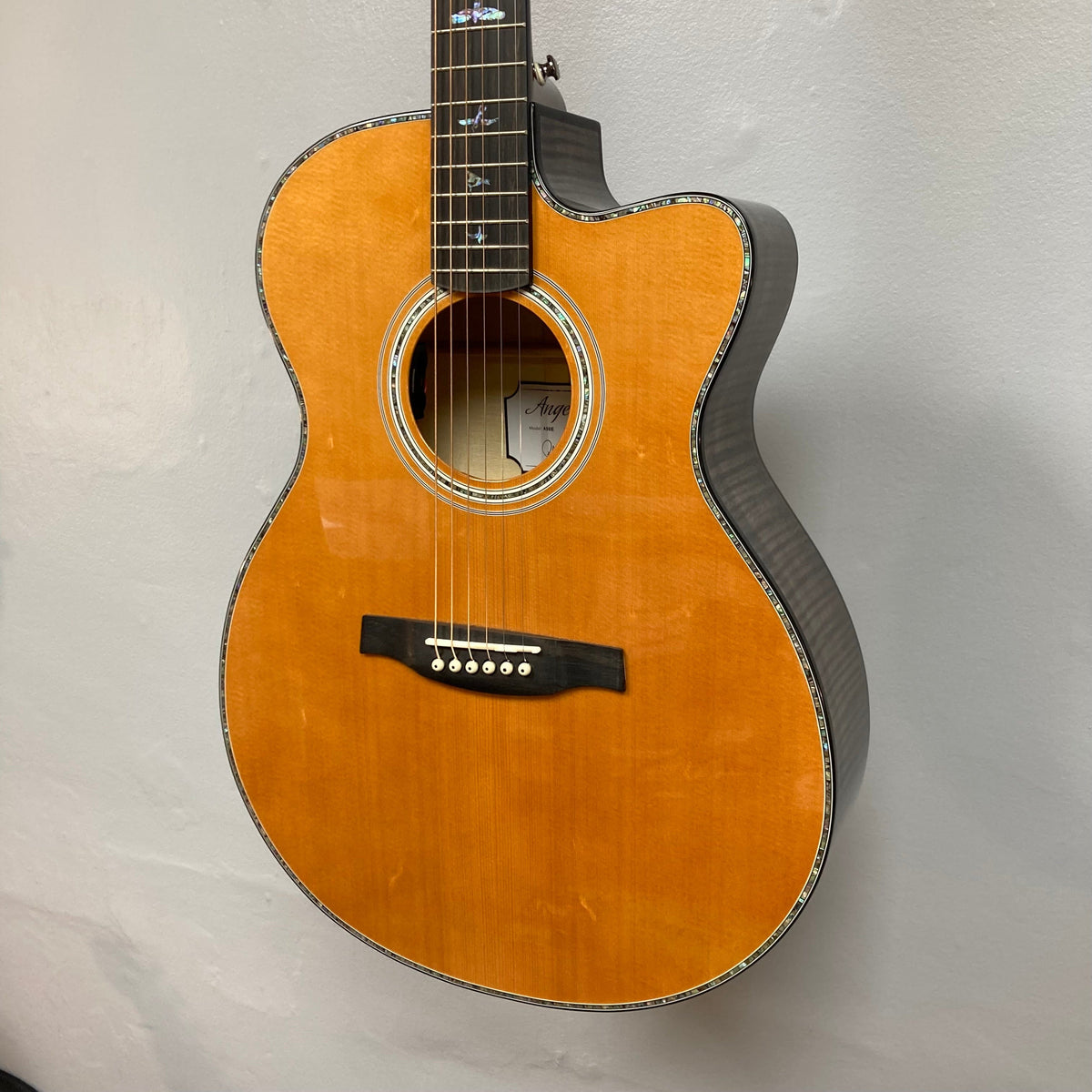 PRS SE A50E Charcoal Burst guitar with maple back, spruce top, PRS bird inlays, and Fishman GT1 pickup system displayed on a wall.