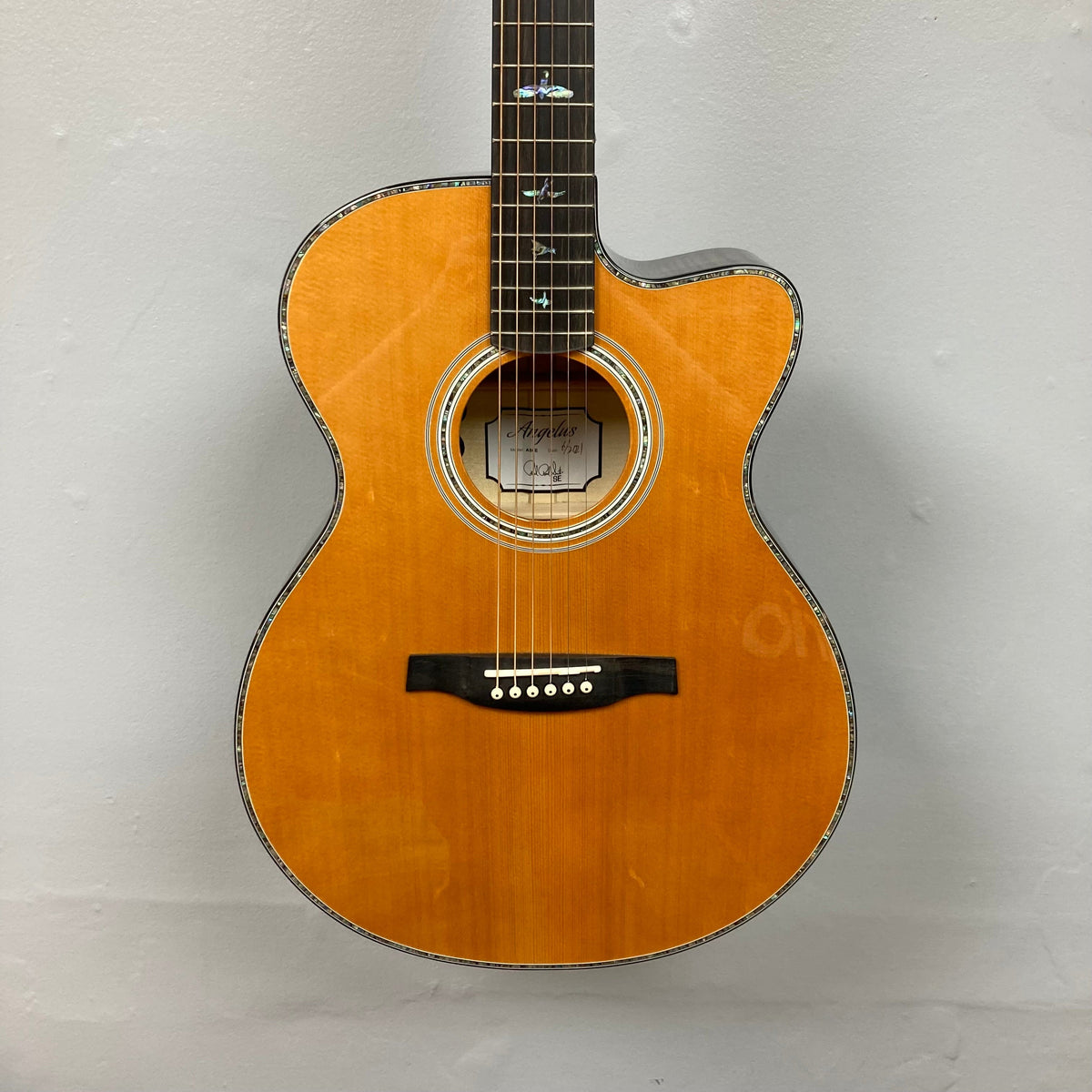 PRS SE A50E Charcoal Burst acoustic guitar with bird inlays, maple back, solid spruce top, and Fishman GT1 pickup system, displayed on a wall.
