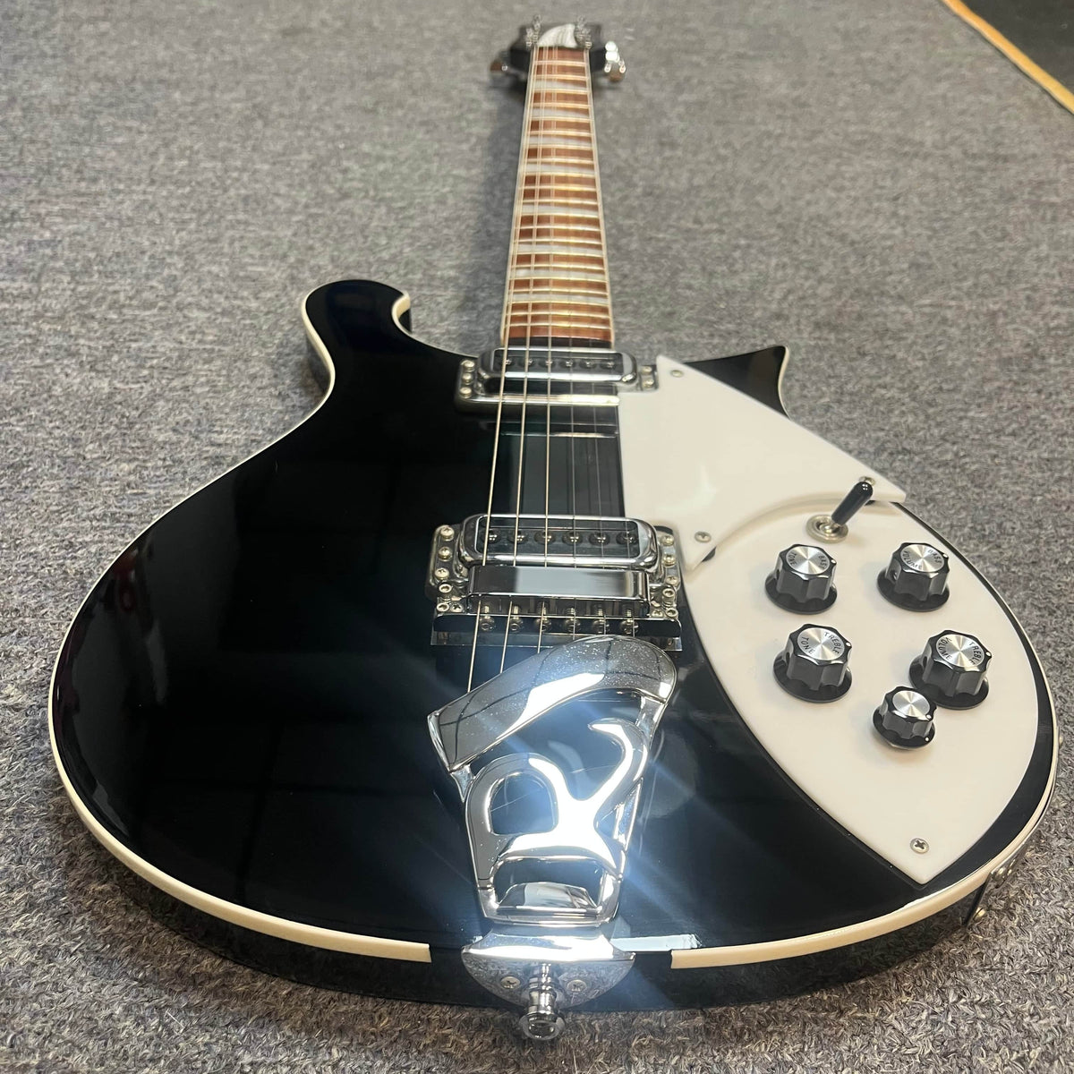 A near-mint Rickenbacker 620 Jetglo with original case is displayed on a grey carpeted surface.
