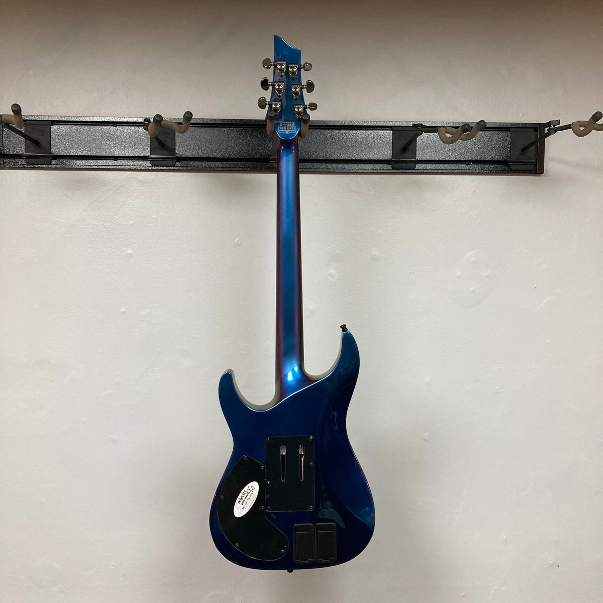 Schecter Hellraiser Hybrid C-1 FR S Sustainiac Ultra Violet Used, displayed on a wall, showcasing its electric guitar design with black knobs and a sleek finish.