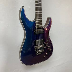 Schecter Hellraiser Hybrid C-1 FR S Sustainiac Ultra Violet electric guitar with distinct pickups and Floyd Rose tremolo, displayed on a wall.