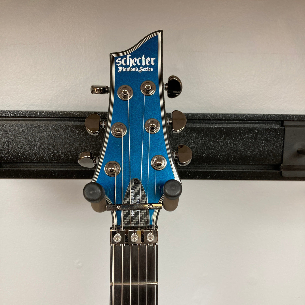 Schecter Hellraiser Hybrid C-1 FR S Sustainiac guitar on a stand, showcasing its Ultra Violet finish and black chrome hardware.