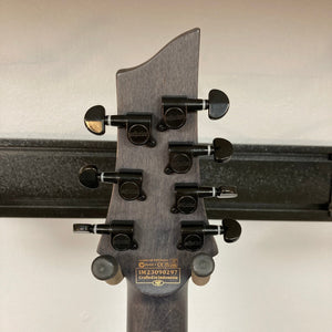 Schecter Omen Elite-7 Left-handed guitar with multiple control knobs, Heretic pickups, and a burl top.