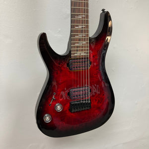 Schecter Omen Elite-7 Left-handed Black Cherry Burst Blemish, red electric guitar with seven strings and Heretic pickups, displayed against a white wall.