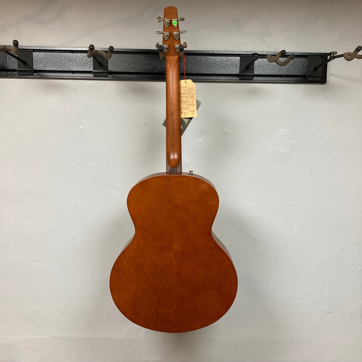 Seagull Entourage Mini Jumbo Rustic Burst MJ guitar displayed on a wall, highlighting its refined cream binding and rustic wood grain finish.