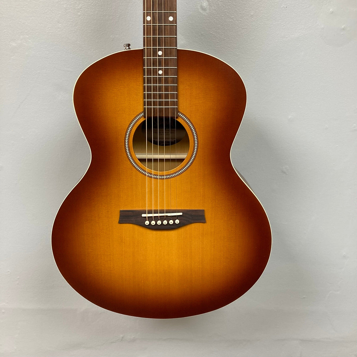 Seagull Entourage Mini Jumbo Rustic Burst MJ guitar, close-up of strings and body, showcasing rustic finish and detailed craftsmanship.