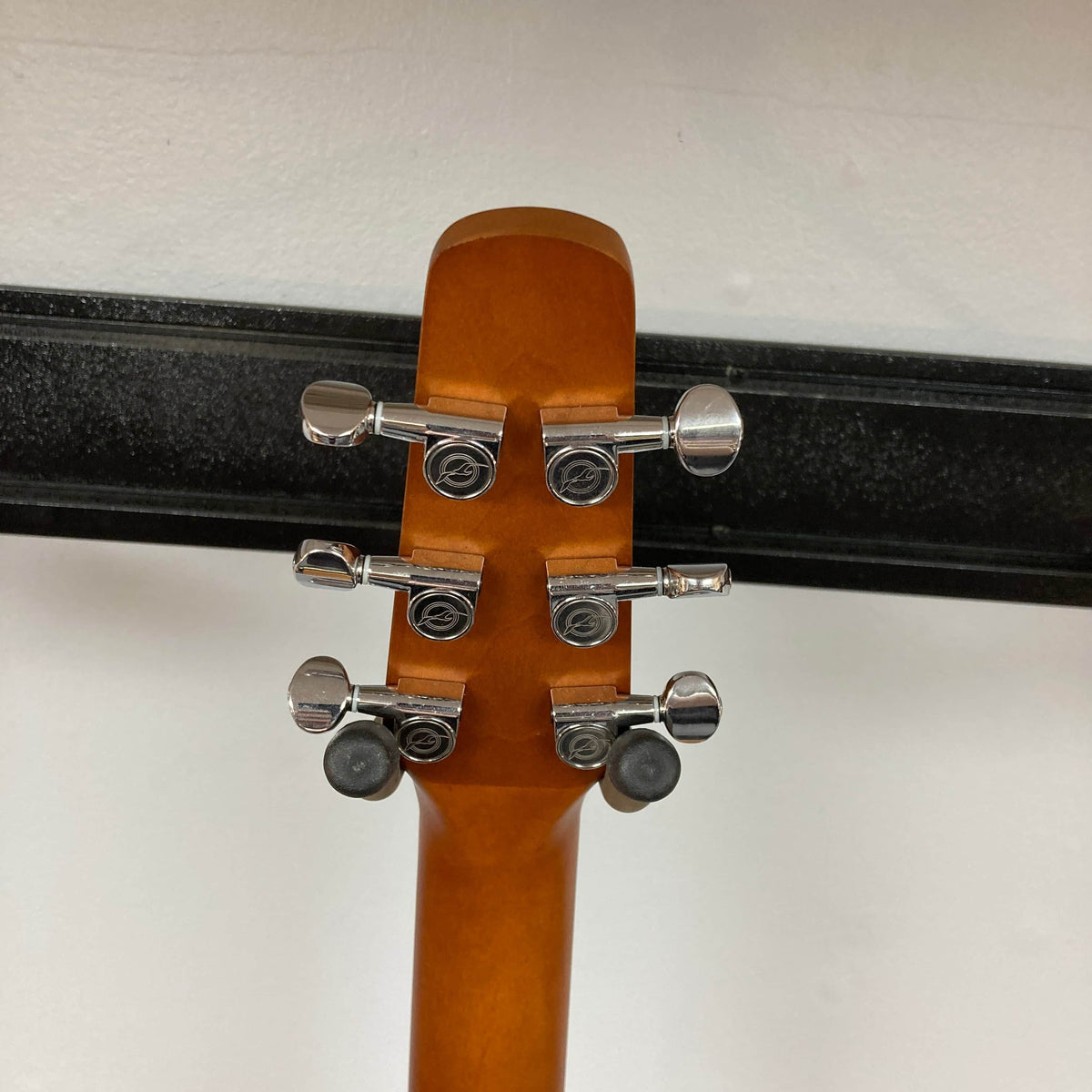 Back of a Seagull S6 QI Slim Acoustic Guitar w/Hard Case - USED/consign headstock, showing six tuning pegs and part of the neck, with a black hanger and white wall—travel-friendly solid spruce top acoustic by Seagull.
