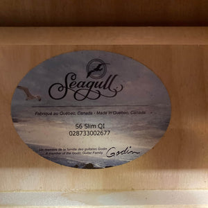 Label inside the Seagull S6 QI Slim Acoustic Guitar (USED/consign) shows serial number 028733002677; made in Quebec, Canada. Travel-friendly with solid spruce top, it is part of the Godin Guitar Family and includes a hard case.