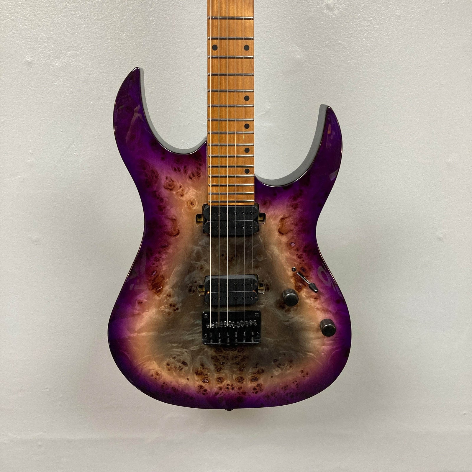 The Spira S-450 Trans Purple TPP electric guitar by Spira features a natural wood and purple burst finish, a modern D profile neck, double-cutaway body, two Villain humbuckers, tremolo bridge, and black knobs, shown against a white wall. The Spira S-450 Trans Purple TPP electric guitar by Spira features a natural wood and purple burst finish, a modern D profile neck, double-cutaway body, two Villain humbuckers, tremolo bridge, and black knobs, shown against a white wall.