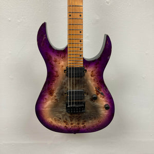 The Spira S-450 Trans Purple TPP electric guitar by Spira features a natural wood and purple burst finish, a modern D profile neck, double-cutaway body, two Villain humbuckers, tremolo bridge, and black knobs, shown against a white wall.