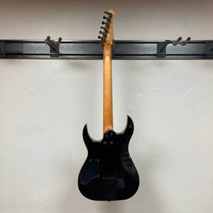 The Spira S-450 Trans Purple TPP electric guitar by Spira hangs on a wall mount, displaying its modern D profile neck, body, and neck against a plain white wall, with tuning pegs and headstock visible at the top.