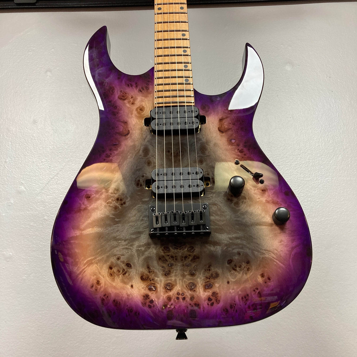 A close-up of the Spira S-450 Trans Purple TPP electric guitar by Spira, featuring a natural wood grain finish, Villain humbuckers, three control knobs, and a sleek 6-string maple neck with a modern D profile.
