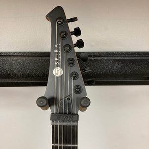 Close-up of the Spira V-400 MBK guitar headstock, featuring six tuning pegs and Spira branding against a light wall background, highlighting its excellent tuning stability.