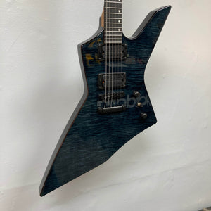 The Spira X-500 TBK E by Spira is a metal guitar with a dark, angular body, locking tuners, and high-output humbuckers, shown against a plain white wall.