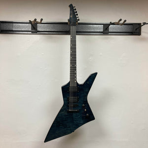 A Spira X-500 TBK E guitar by Spira, featuring a dark blue metal finish, angular asymmetric body, and high-output humbuckers, hangs on a wall-mounted rack against a white background.