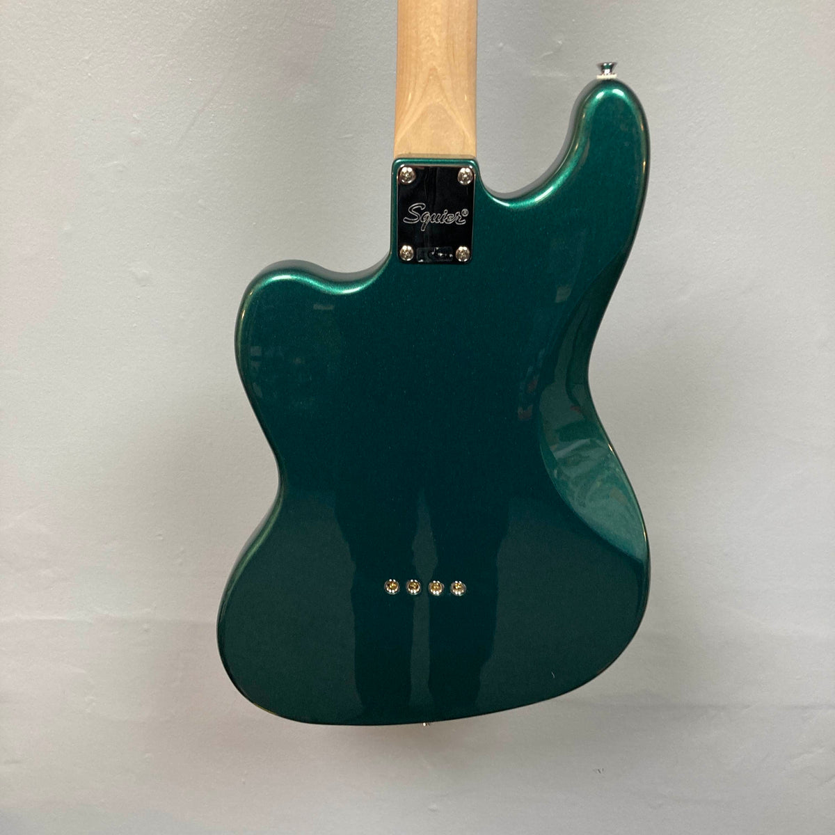 Back view of a Squier Paranormal Rascal Bass HH Sherwood Green Refurb, a short scale bass by Squier featuring a natural wood neck, metal neck plate stamped with “Squier,” and four visible screws on the body, shown against a plain light background.