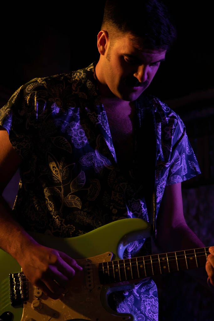 Man playing a green electric guitar. Man playing a green electric guitar.