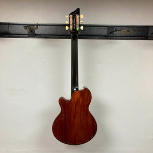 Back view of a Supro 1296 Silverwood British Racing Green w/Gigbag Used electric guitar by Supro hanging on a wall-mounted rack against a plain white background, highlighting its classic design and subtle Gold Foil pickups.