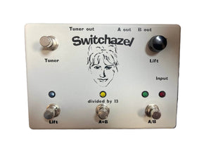The Switchazel Boutique AB/Y Switcher with Tuner Out (Preowned) by Switchazel features five switches, indicator lights, and multiple I/O jacks on a metallic panel for seamless ground loop elimination.