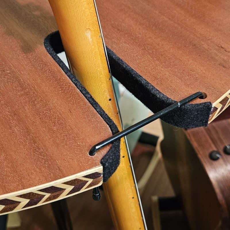 The Carousel™ Deluxe Rotating Guitar Stand by A&S Crafted Products features a wooden shelf with a notched cutout that fits around a vertical pole, secured by a black Allen wrench and lined with black felt for guitar protection.