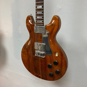 Travis Bean TB1000A Artist Natural 1970s electric guitar displayed on a wall, showcasing its unique aluminum neck and original pickups.