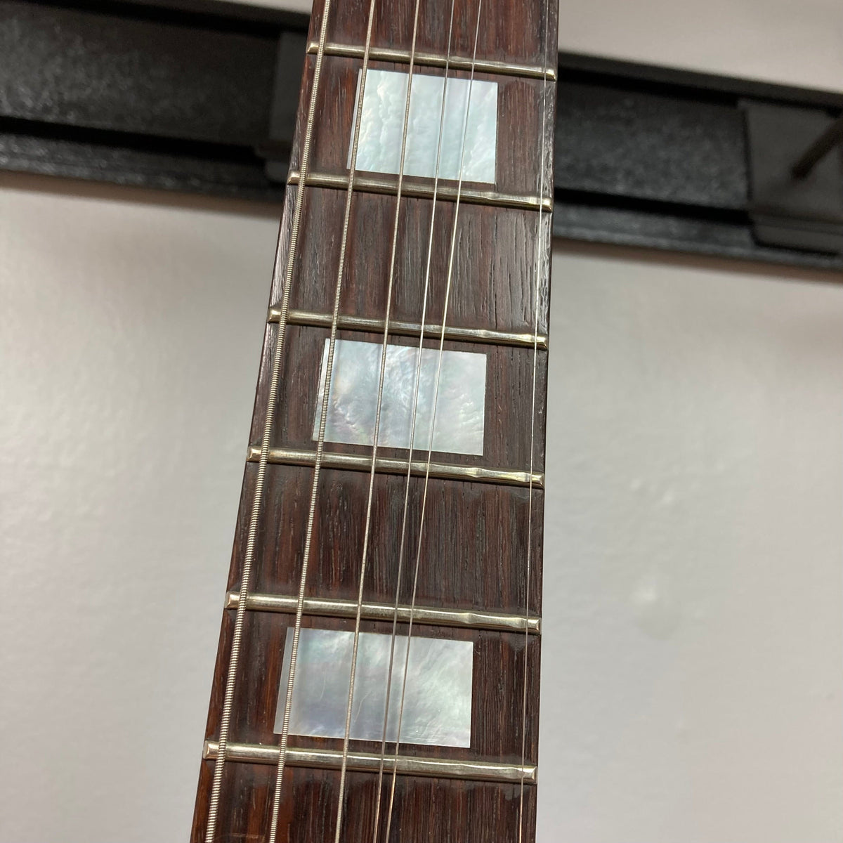 Close-up of Travis Bean TB1000A Artist Natural 1970s guitar strings and body, highlighting its aluminum neck and original pickups.