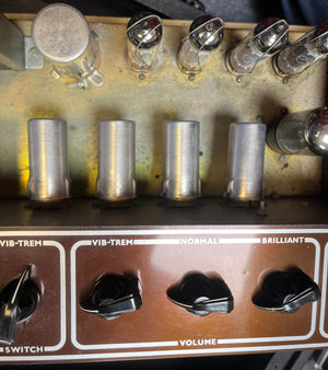 Close-up of a Vintage 1963 Vox AC30/6 Normal amplifier control panel by Vox, featuring labeled knobs, switches, visible vacuum tubes, metal covers, and original JMI Egg Footswitch with Flight Case—all delivering classic tone.