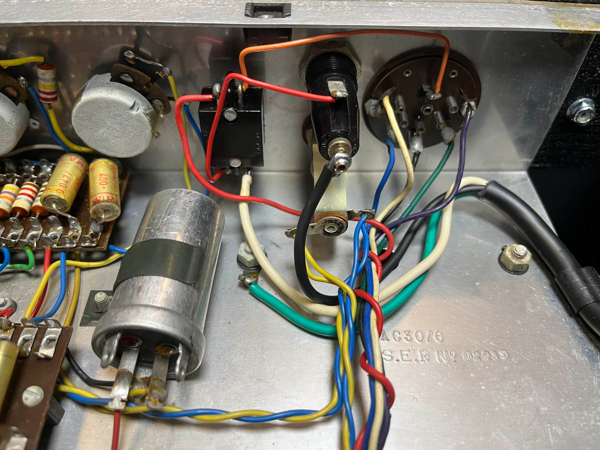 Close-up of electronic components and wiring inside a Vintage 1963 Vox AC30/6 Normal by Vox, featuring original JMI egg footswitch and flight case, with classic resistors, capacitors, and colored wires typical of vintage amplifiers.
