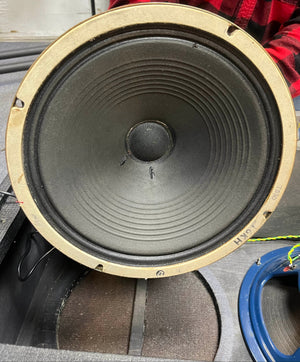 A close-up of a round speaker cone with two small center tears, mounted in a Vintage 1963 Vox AC30/6 Normal by Vox, featuring the original JMI Egg Footswitch and Flight Case.