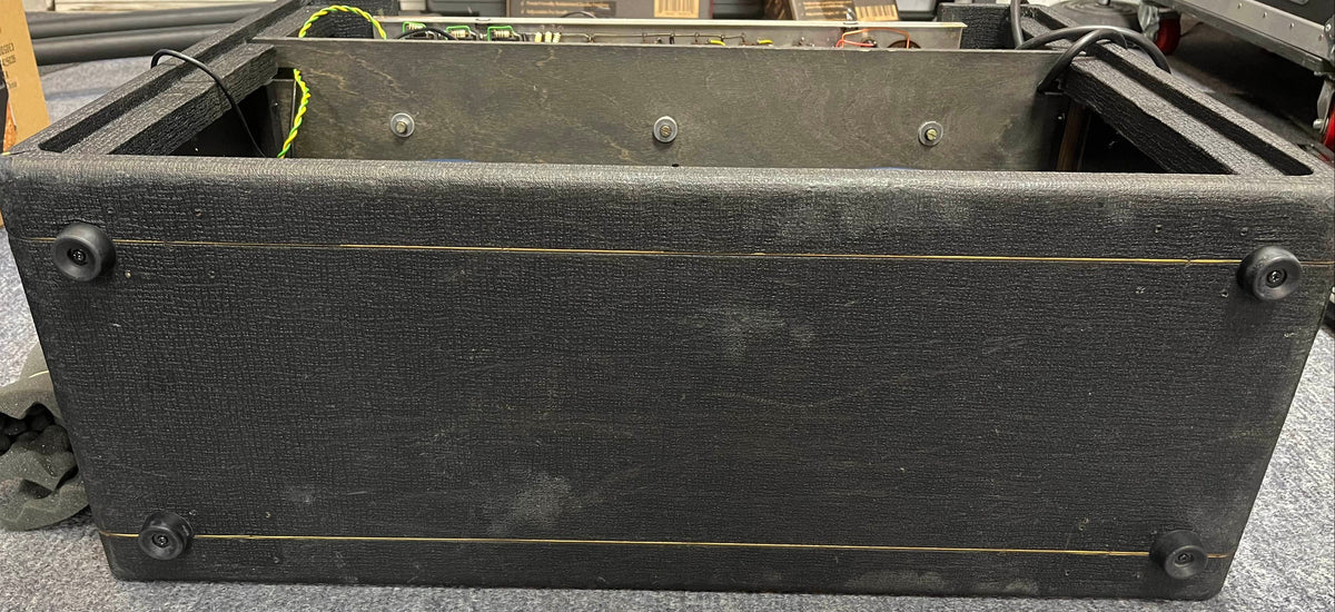 A vintage 1963 Vox AC30/6 Normal amplifier by Vox, shown from below with its original JMI egg footswitch and flight case. Four rubber feet and some surface wear are visible.