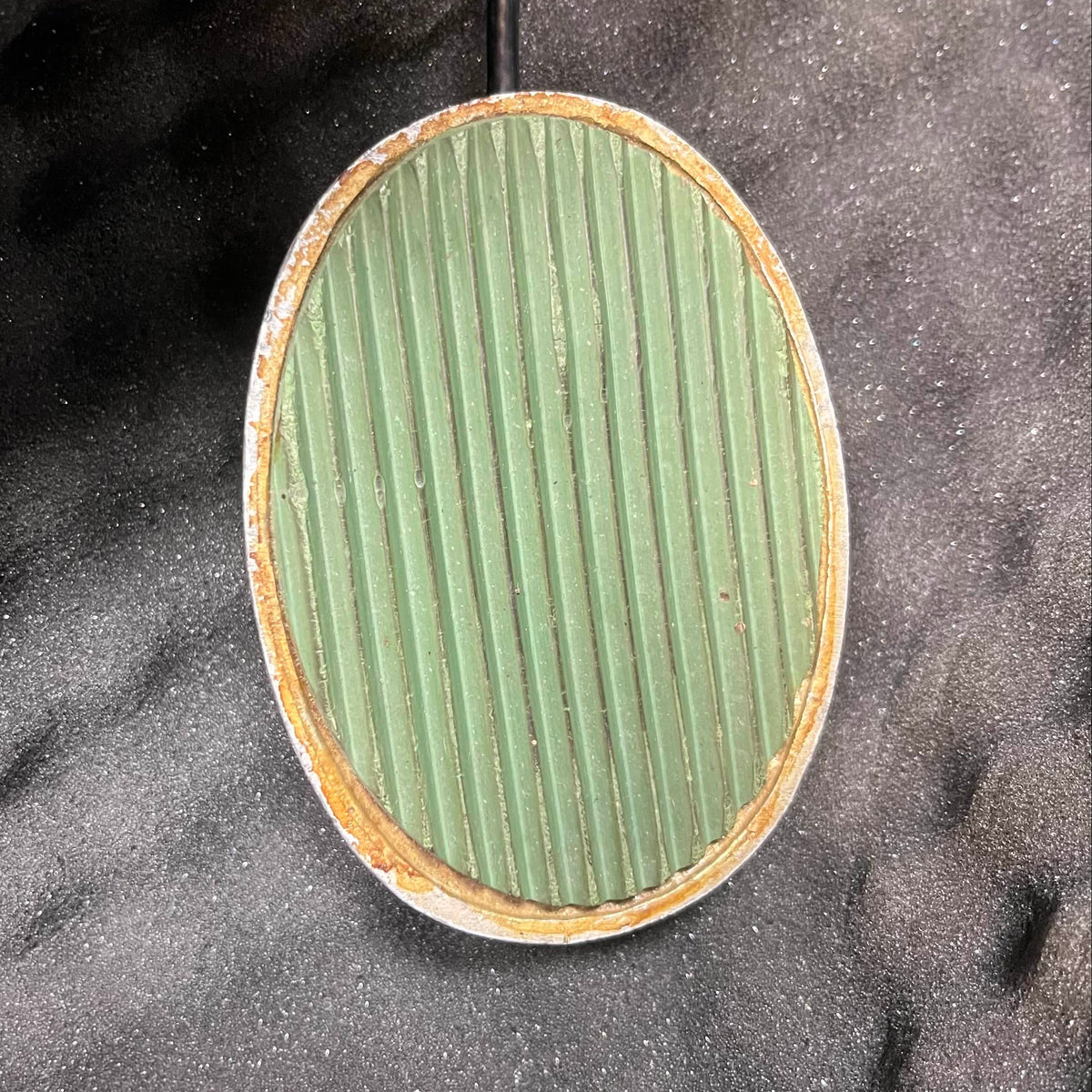 A round, green, ribbed object—similar to a Celestion Blue T530 speaker—rests on a black surface beside a Vintage 1963 Vox AC30/6 Normal amp with the original JMI Egg footswitch and flight case from Vox.