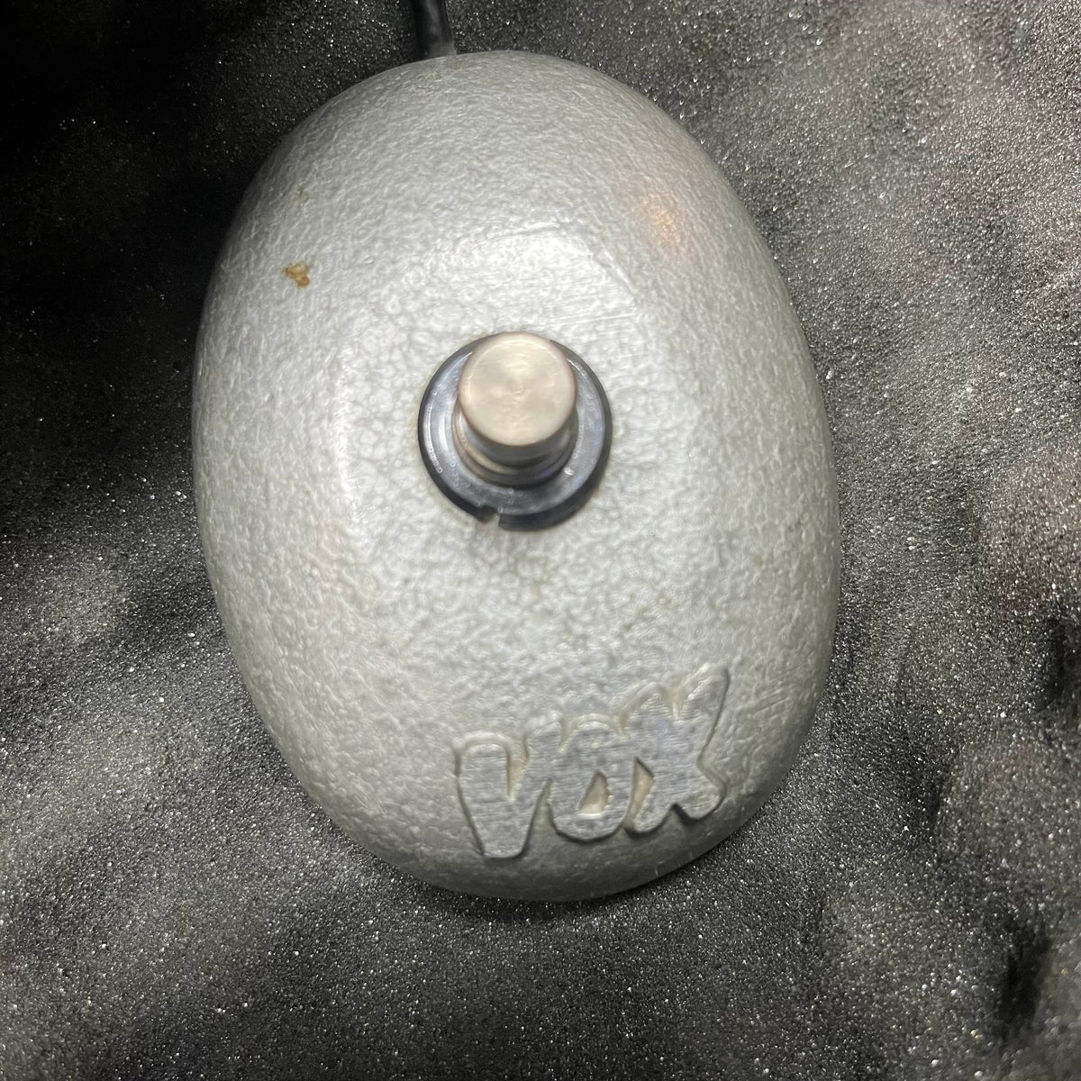 A vintage 1963 Vox AC30/6 Normal with original JMI egg footswitch—an oval gray switch with a metal button—and flight case by Vox is shown on a foam background.