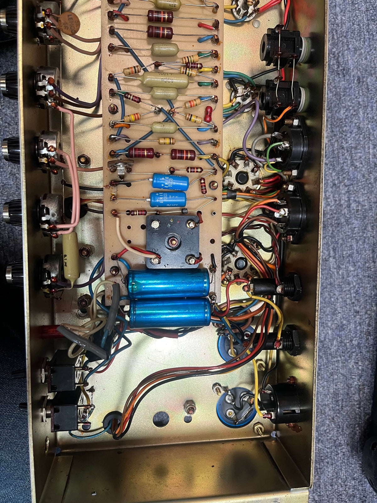 Interior of a vintage Marshall 1971 Lead Head JMP 1987 50W amp, showing circuit board with capacitors, resistors, wires, and jacks on metallic chassis—inspired by the iconic Marshall sound. Includes flight case.