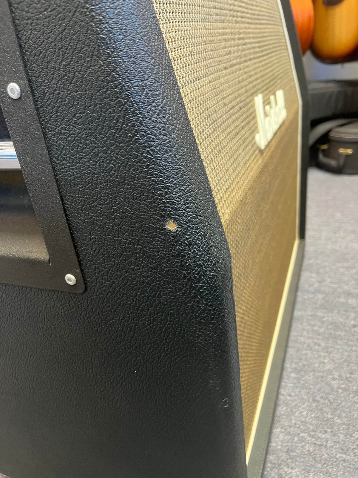 Close-up of a 1969 Marshall 4x12 Cabinet with Matching Celestion T1281 Greenbacks showing a small dent or scuff mark on the black textured vinyl covering near the front edge.