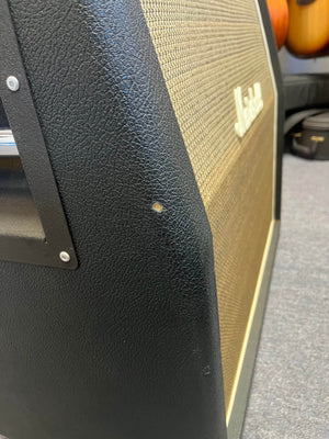 Close-up of a 1969 Marshall 4x12 Cabinet with Matching Celestion T1281 Greenbacks showing a small dent or scuff mark on the black textured vinyl covering near the front edge.