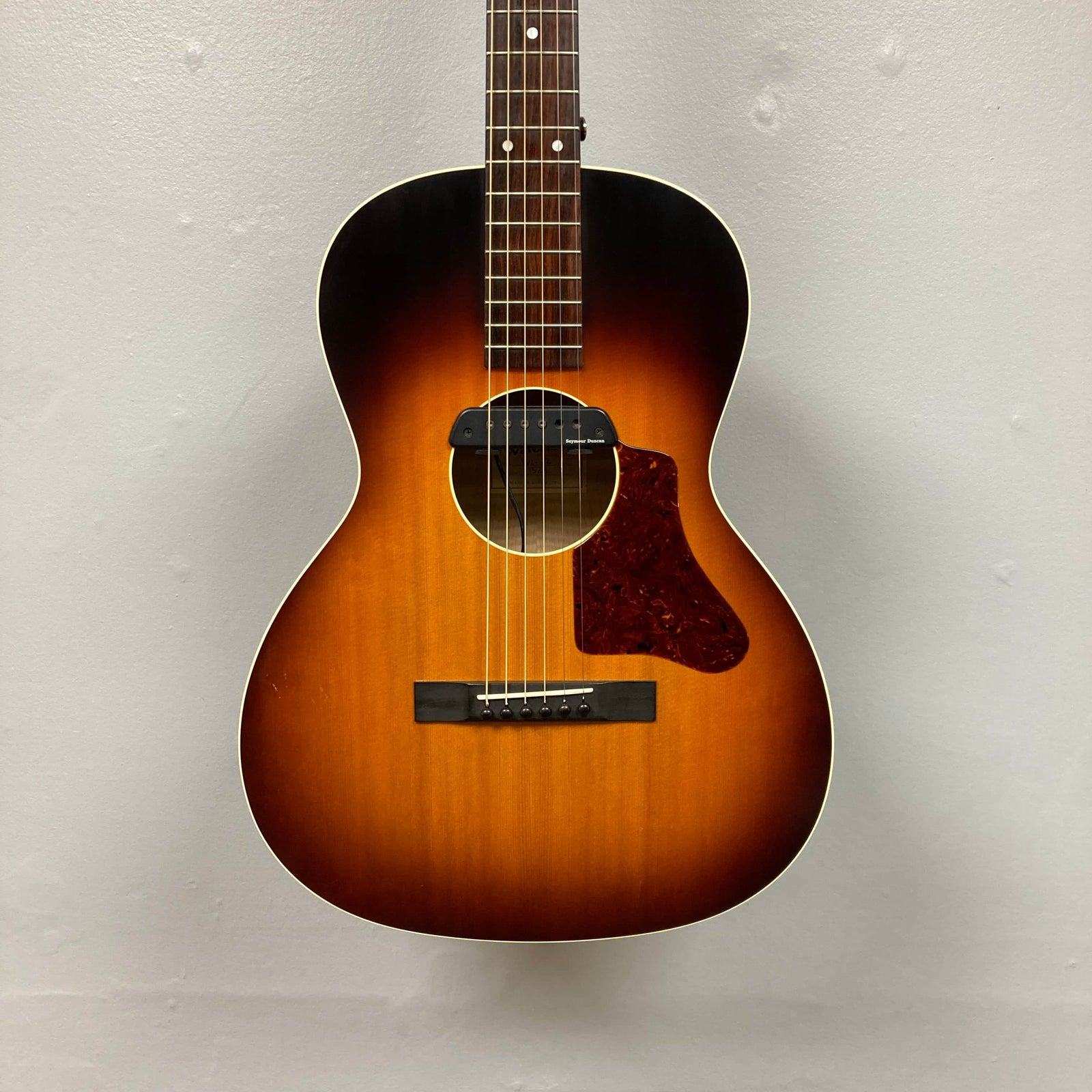 This used Waterloo WL-12 Parlor Acoustic guitar, featuring a sunburst finish, tortoiseshell pickguard, and soundhole pickup, is photographed against an off-white wall. Brand: Waterloo. Includes case. Consignment item. This used Waterloo WL-12 Parlor Acoustic guitar, featuring a sunburst finish, tortoiseshell pickguard, and soundhole pickup, is photographed against an off-white wall. Brand: Waterloo. Includes case. Consignment item.
