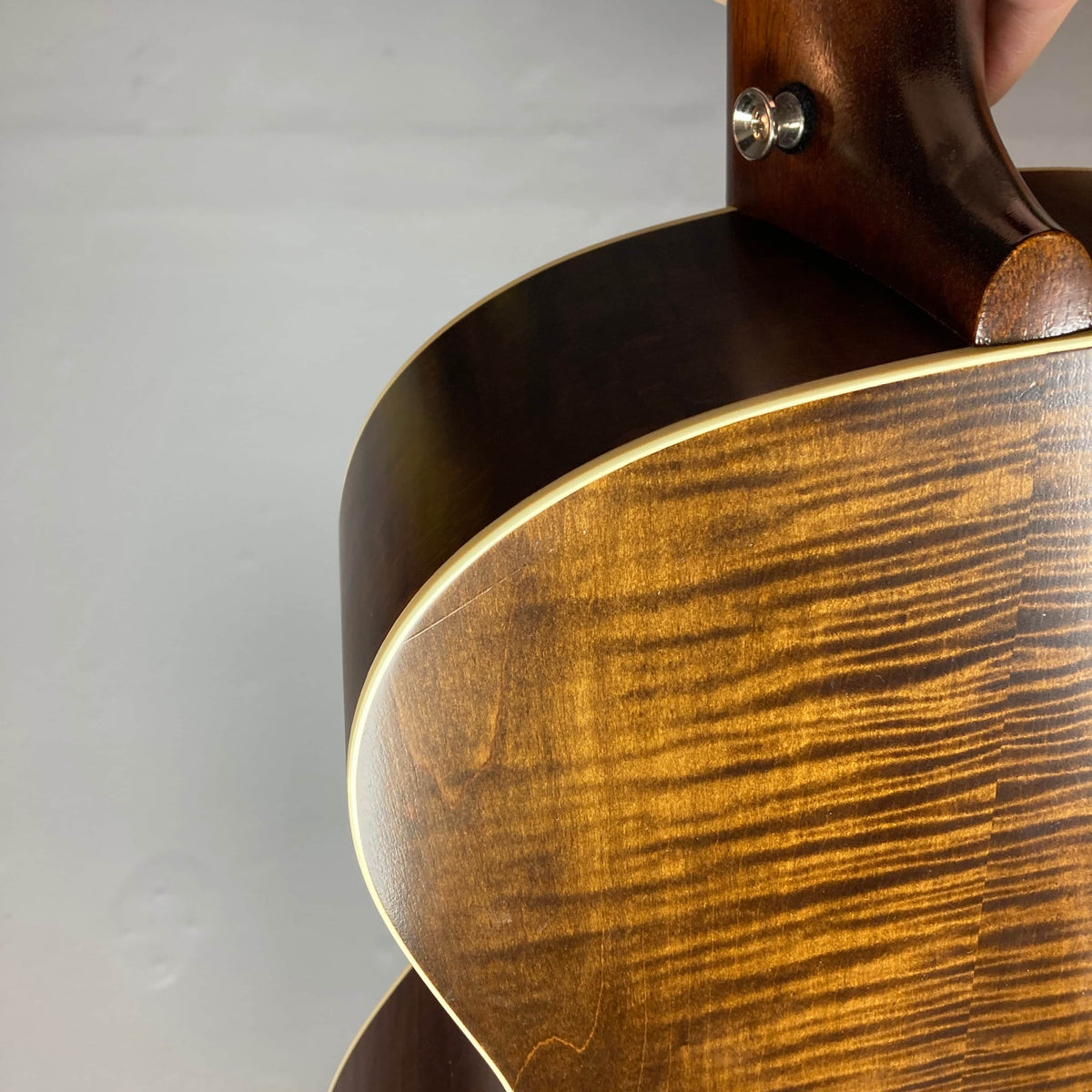 Close-up of the back and neck joint of a Waterloo WL-12 Parlor Acoustic w/Case Used Consign, showing its glossy wood grain finish and cream binding, set against a light background.