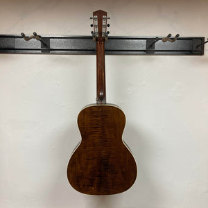 A Waterloo WL-12 Parlor Acoustic w/Case Used Consign guitar by Waterloo hangs on a black wall rack. Shot from behind, its glossy dark wood finish and white binding emphasize the visible wood grain.