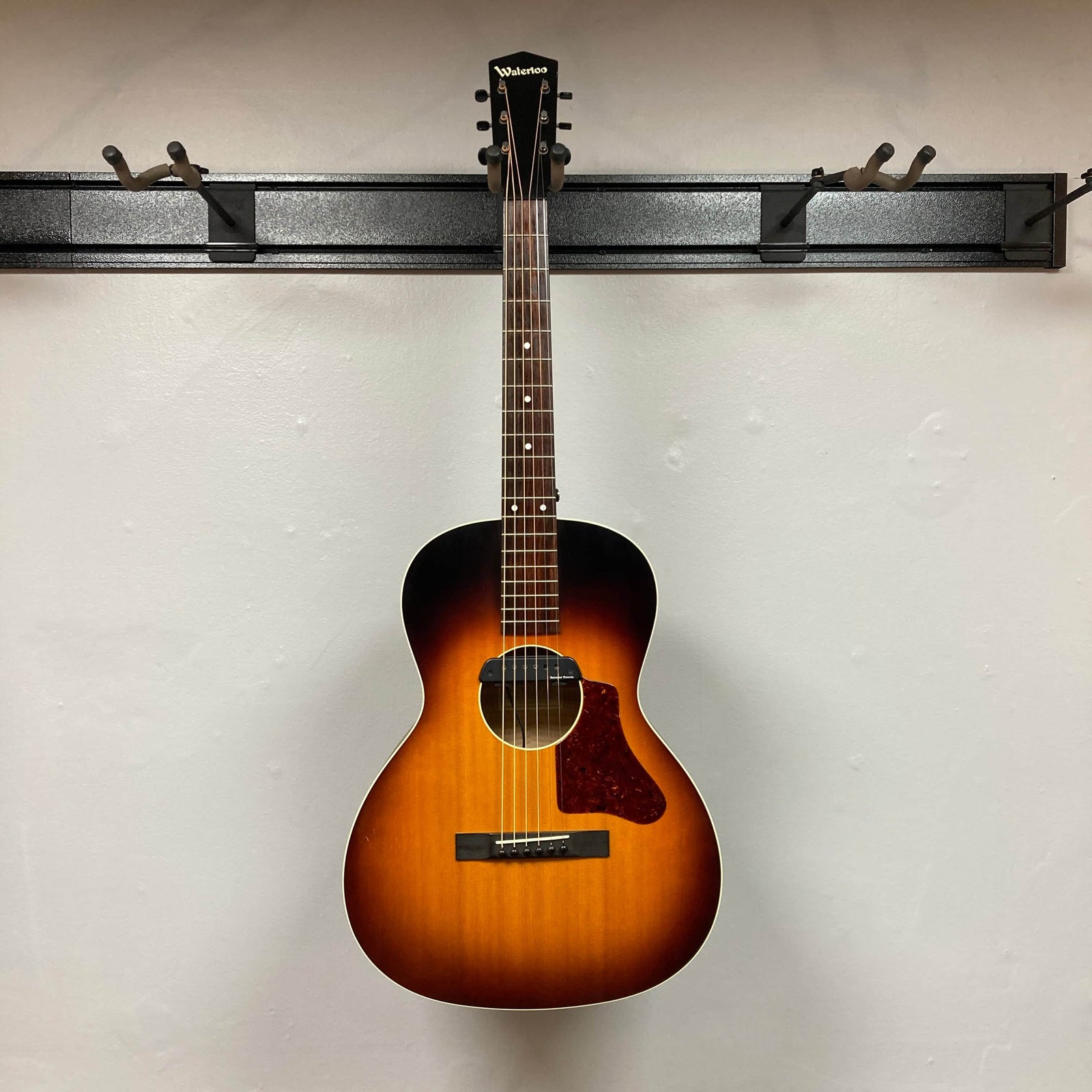 This used Waterloo WL-12 Parlor Acoustic guitar, featuring a sunburst finish, tortoiseshell pickguard, and soundhole pickup, is photographed against an off-white wall. Brand: Waterloo. Includes case. Consignment item. This used Waterloo WL-12 Parlor Acoustic guitar, featuring a sunburst finish, tortoiseshell pickguard, and soundhole pickup, is photographed against an off-white wall. Brand: Waterloo. Includes case. Consignment item.