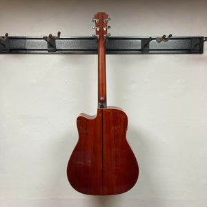 A Yamaha A3M ARE Vintage Natural Acoustic Guitar w/Hard Bag by Yamaha hangs on a black wall-mounted rack, displaying the back of its body and neck against a plain white wall.