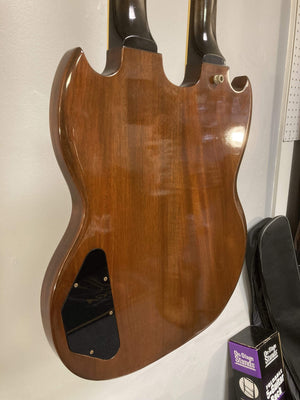 1980 Gibson EDS-1275 Double Neck Electric Guitar hanging on a white wall, showcasing its iconic double-neck design.