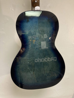 The back of an Art & Lutherie Roadhouse HG Indigo Burst Q-Discrete guitar reflecting light and objects, including the reversed Art & Lutherie logo.