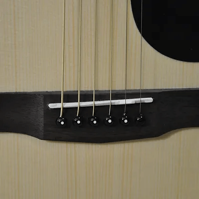 Close-up of the Bodhi BG10E Spruce Top Concert Body Acoustic-Electric Guitar bridge with six strings and black pins on a light wood finish, perfect for fingerpicking guitar enthusiasts.